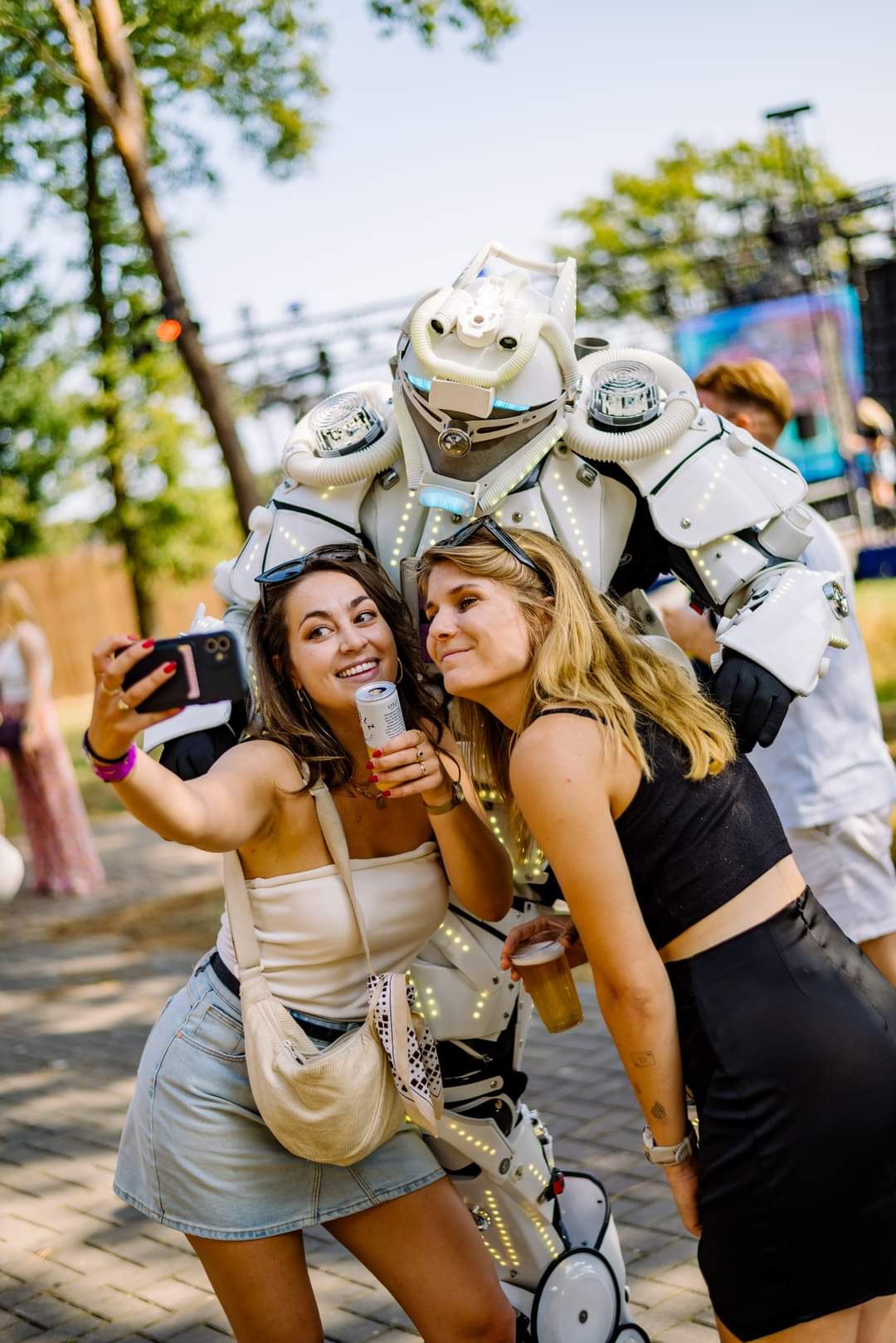 Festivalbezoekers maken een selfie met de LED-robot steltloper