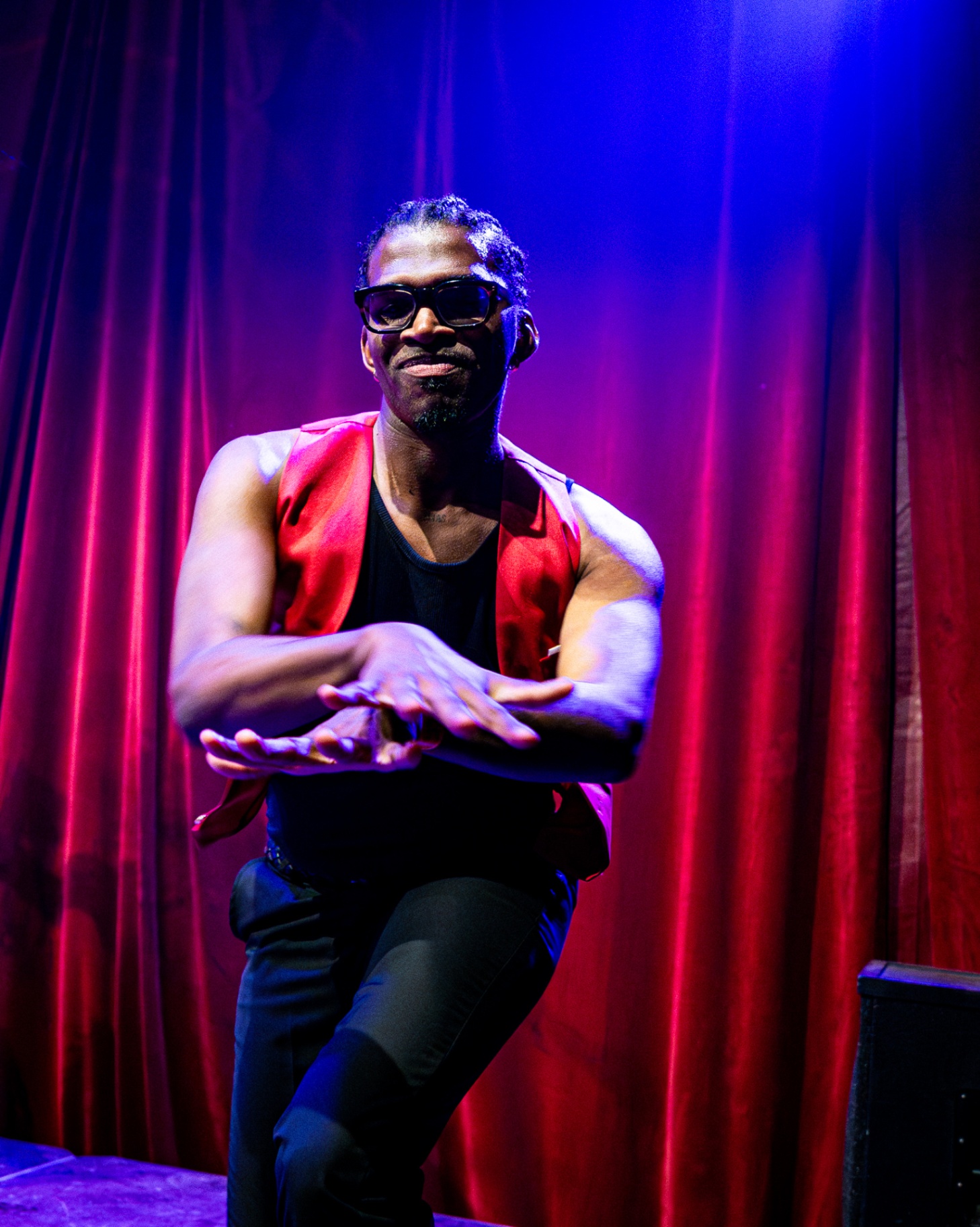 Danser in rood vest voor een rood theatergordijn