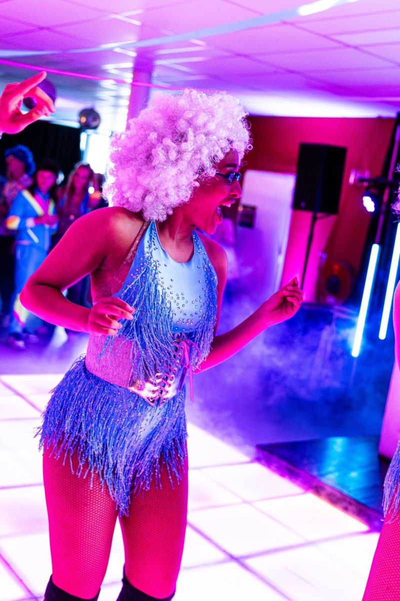 Danseres met witte afropruik en blauw franjekostuum op een disco dansvloer