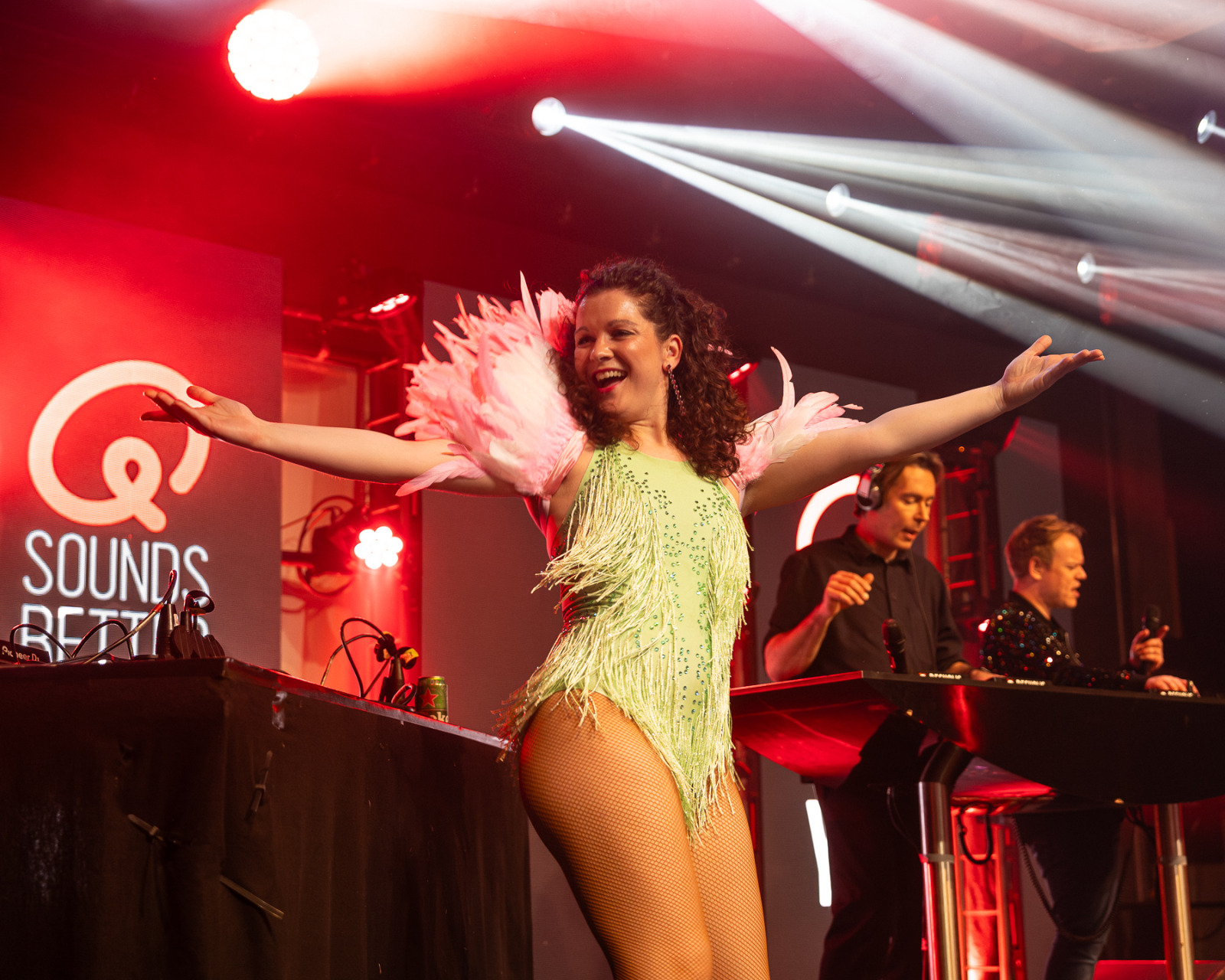 Danseres met roze verenkraag naast de dj's op het Q-music podium