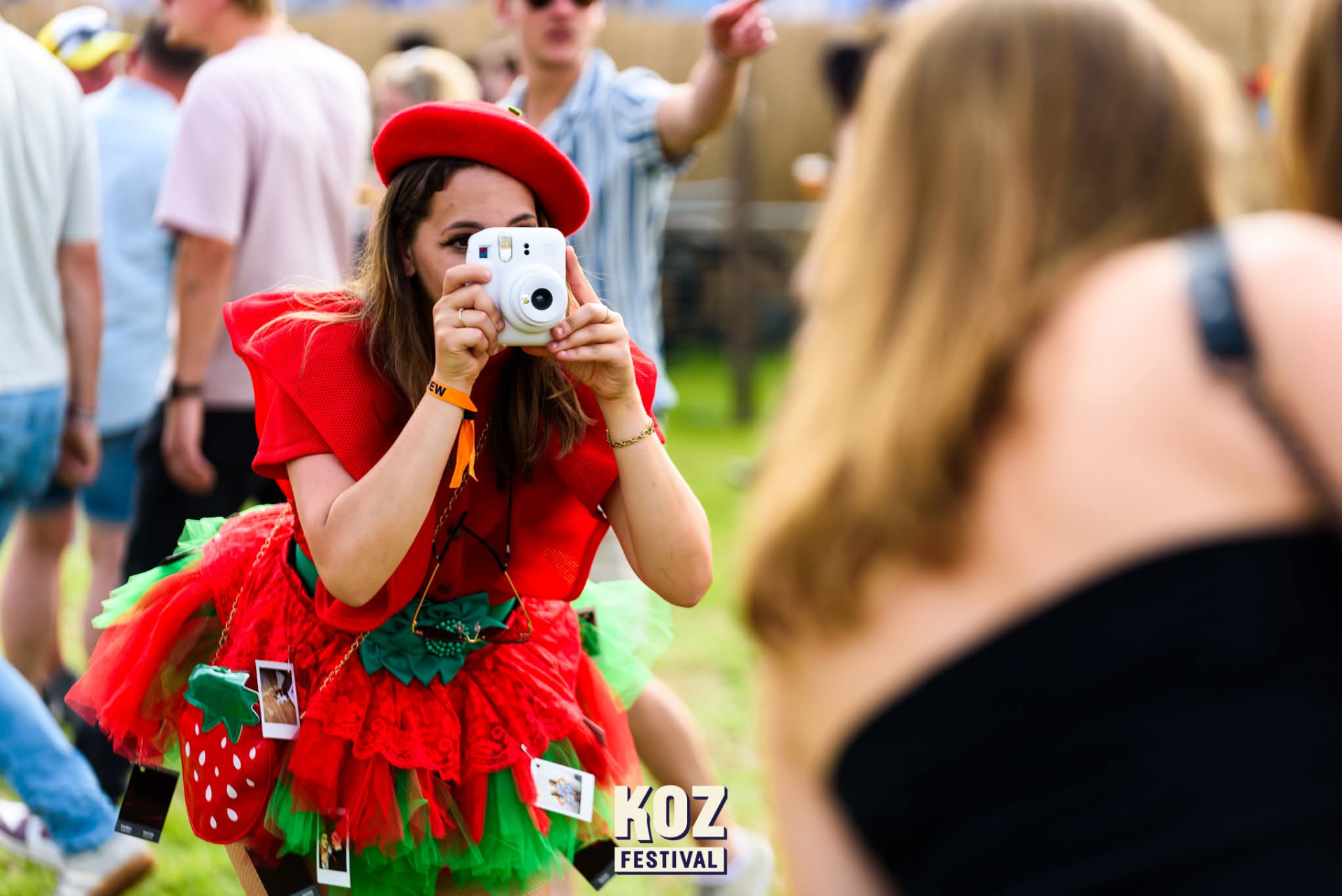 Polaroid Lady in rood aardbeienkostuum fotografeert een festivalgast