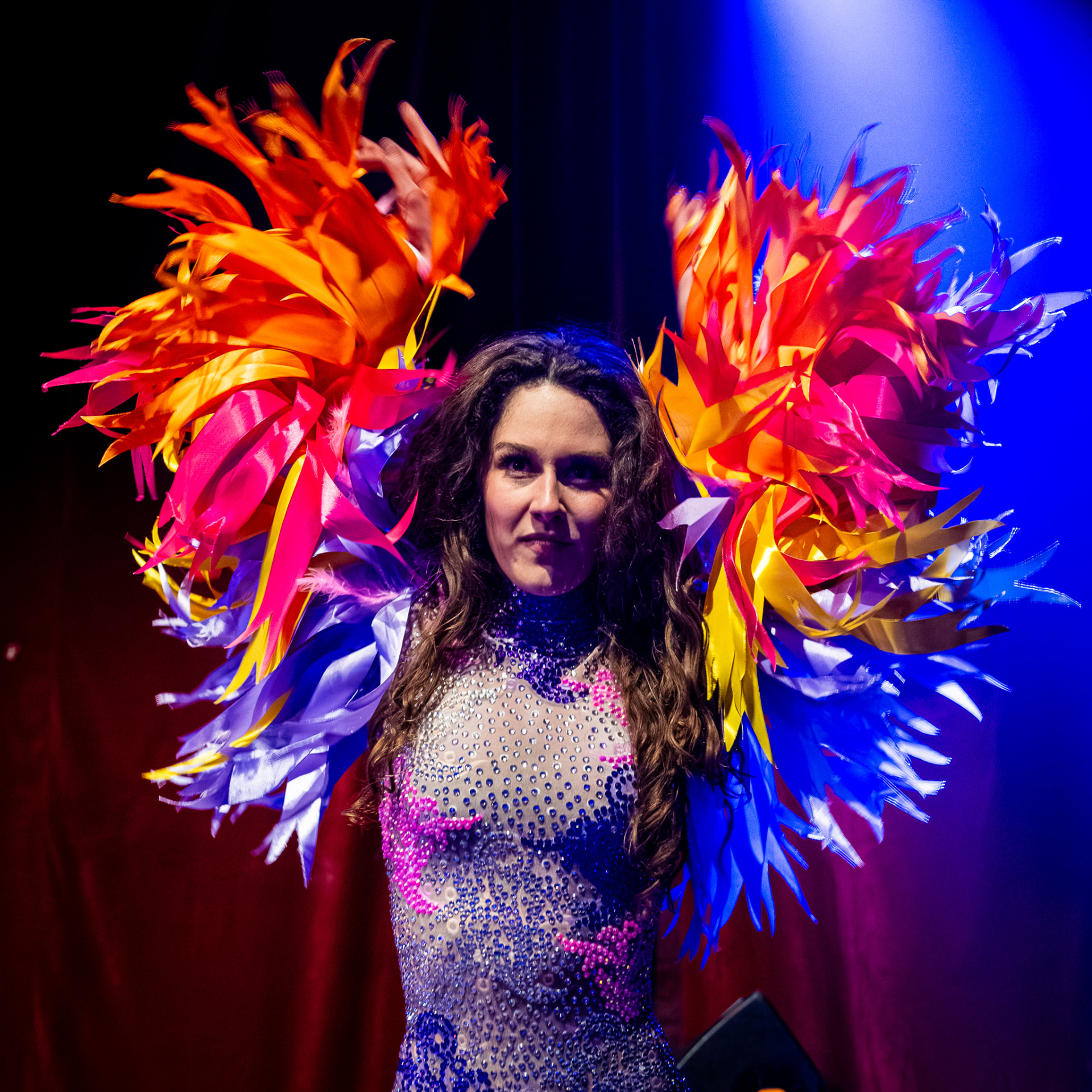 Performer met kleurrijke vleugels van veren op het podium
