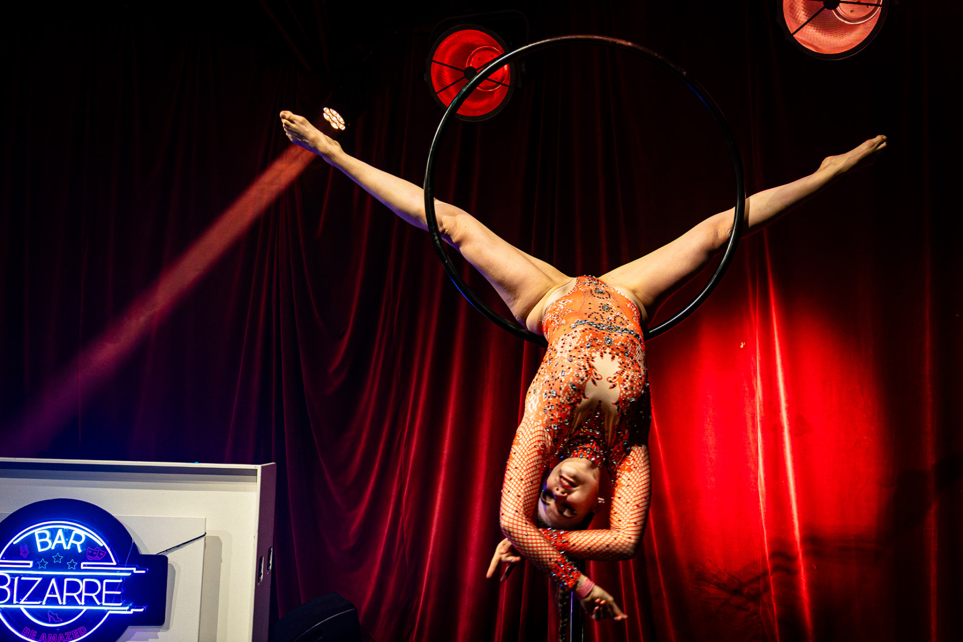 Aerial hoop artiest ondersteboven in de lucht bij rood doek
