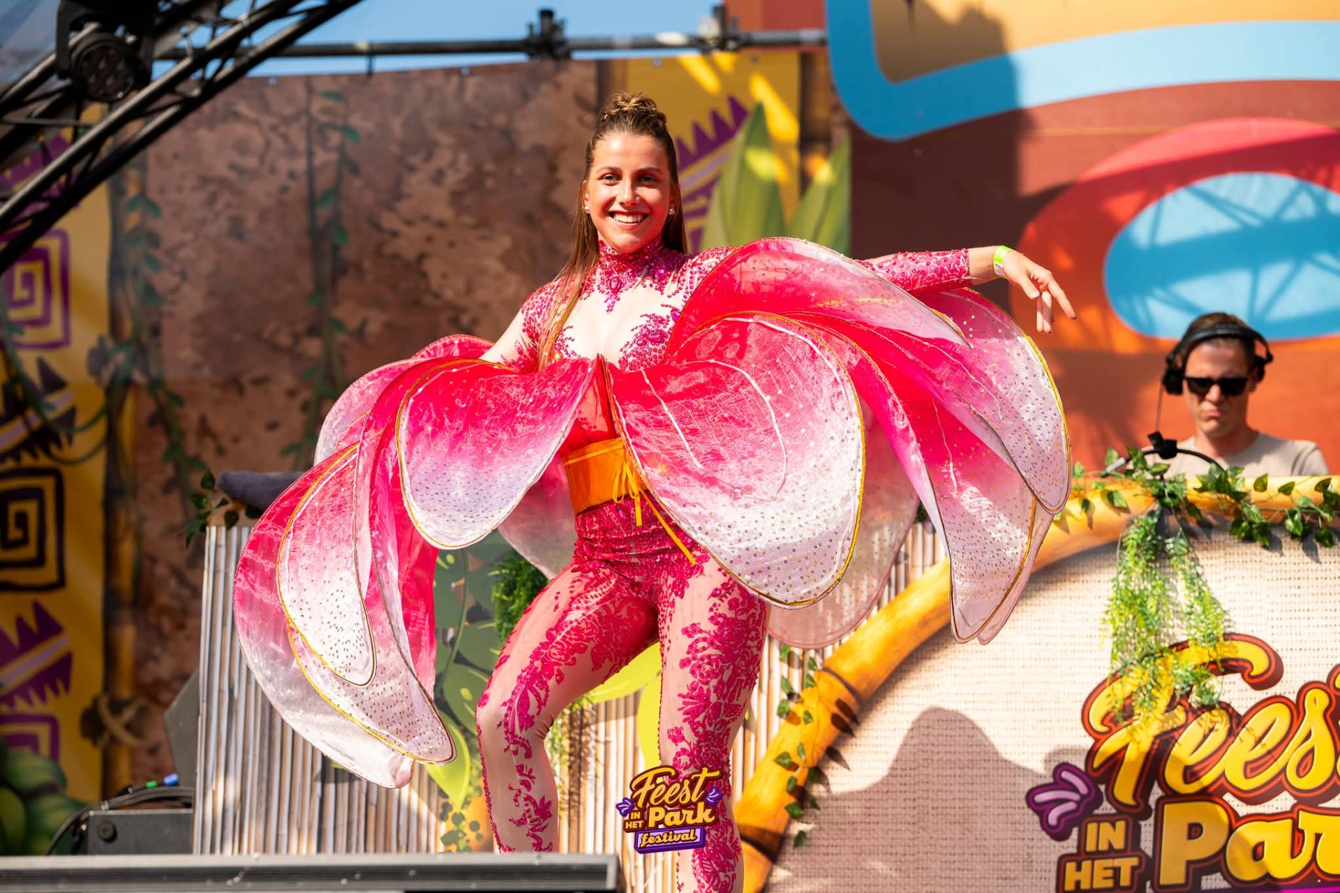 Performer in roze bloemkostuum op het podium van Feest in het Park