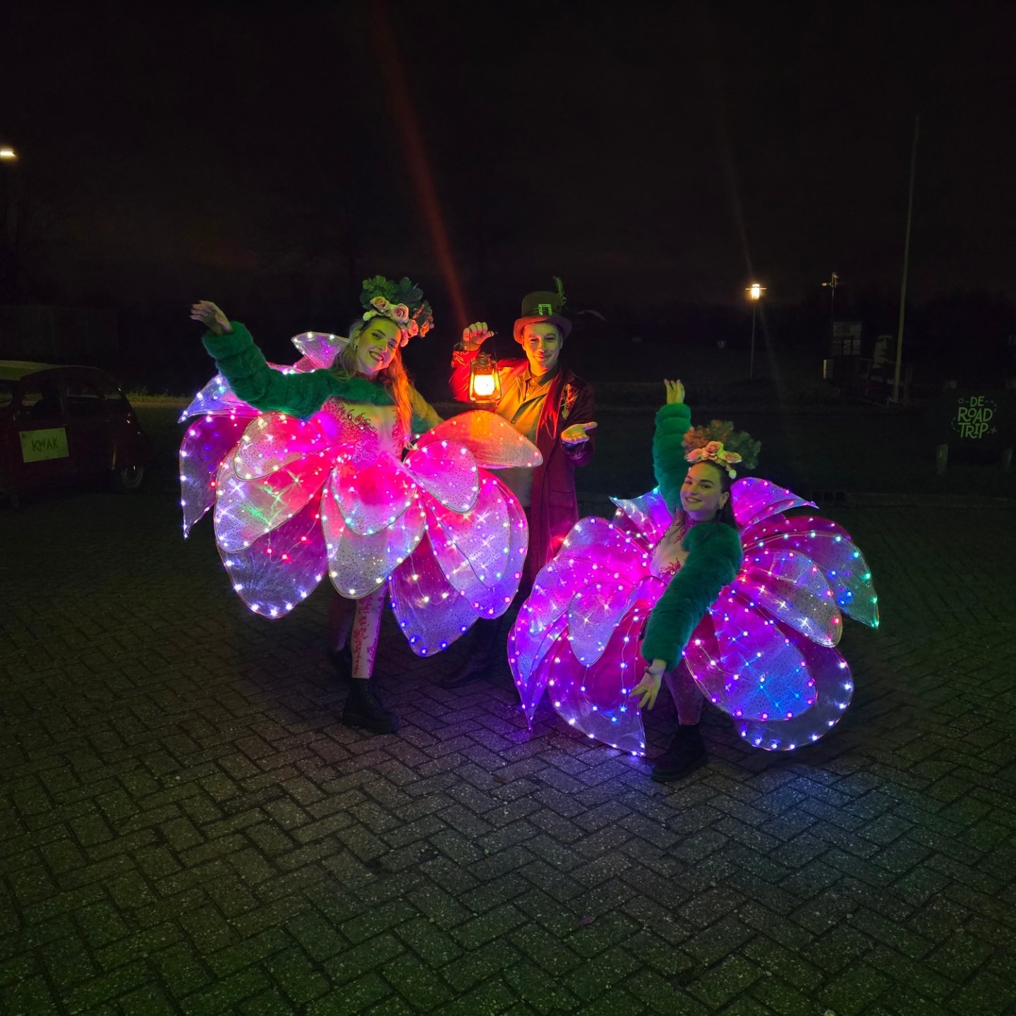 Twee LED-bloemdanseressen en een performer met lantaarn in het donker