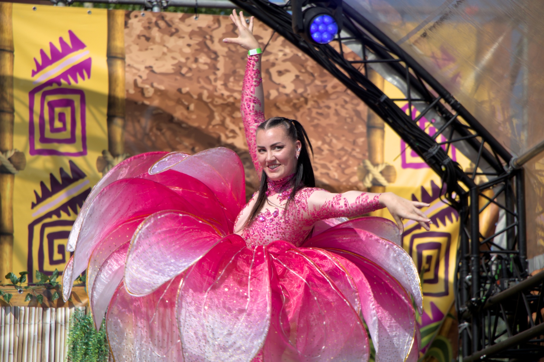 Performer in roze bloemkostuum op een festivalpodium