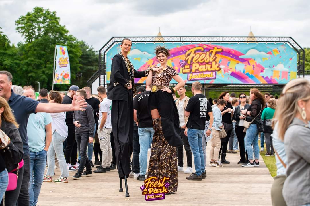 Steltenact Sjonnie en Anita lopen op stelten tussen het publiek voor het festivalpodium