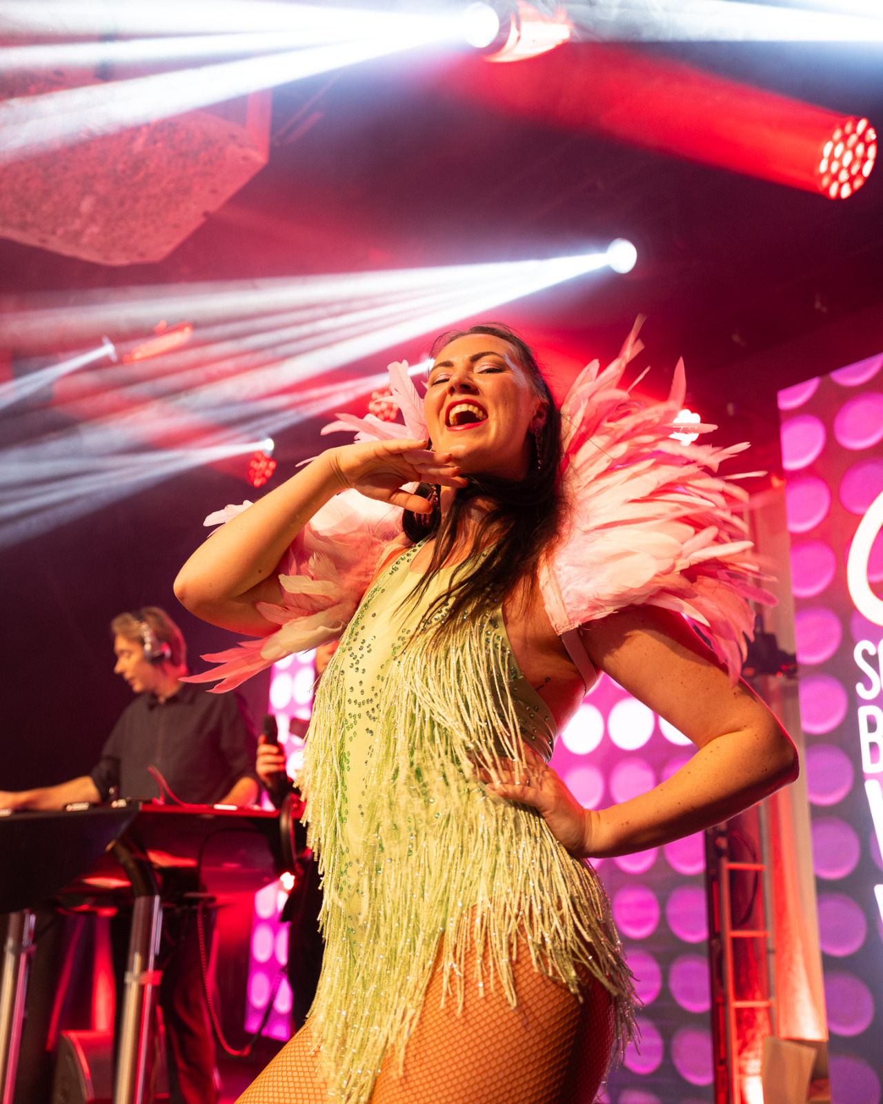 Danseres in groen franjekostuum met roze veren op het Q-music podium