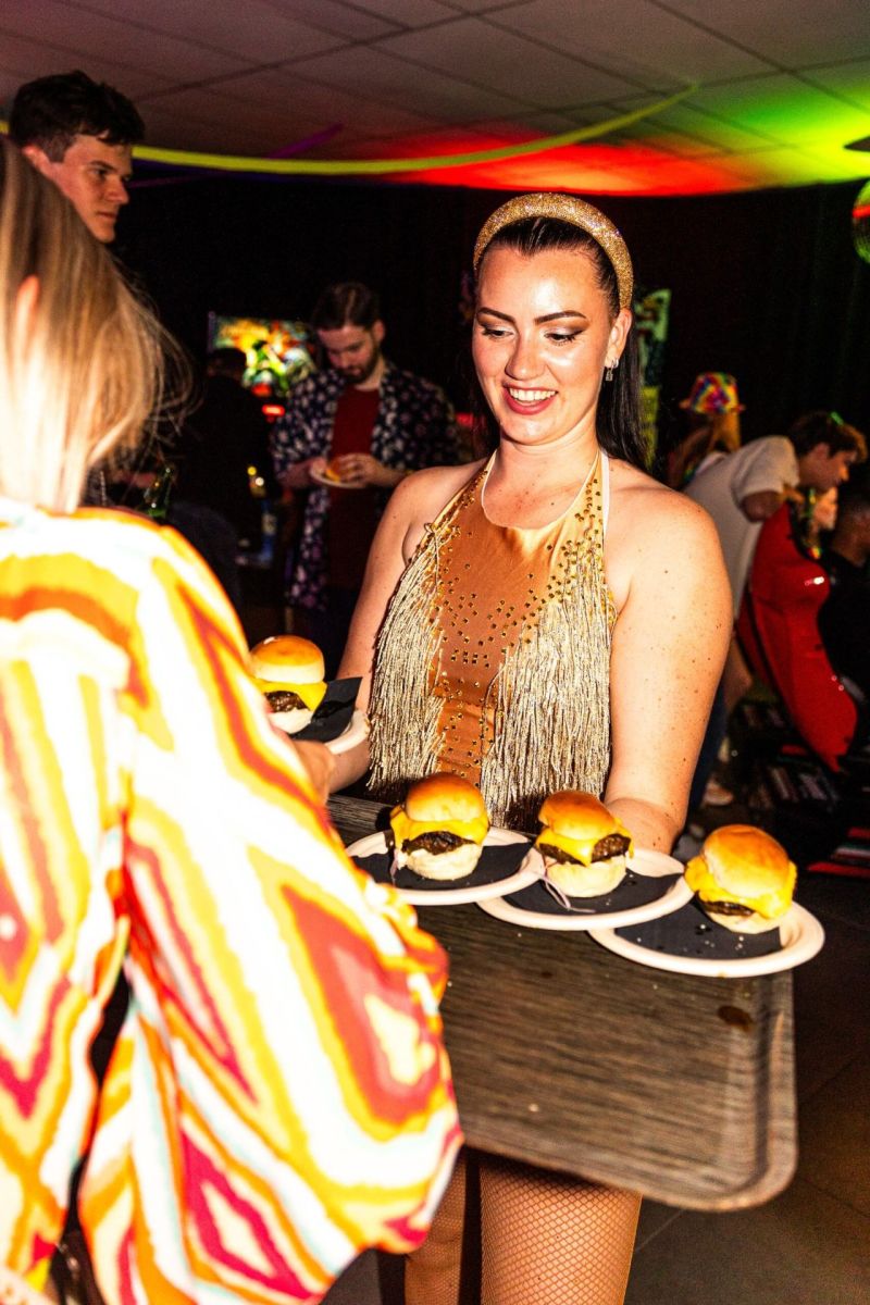 Hostess in gouden franjekostuum serveert hapjes op een feest