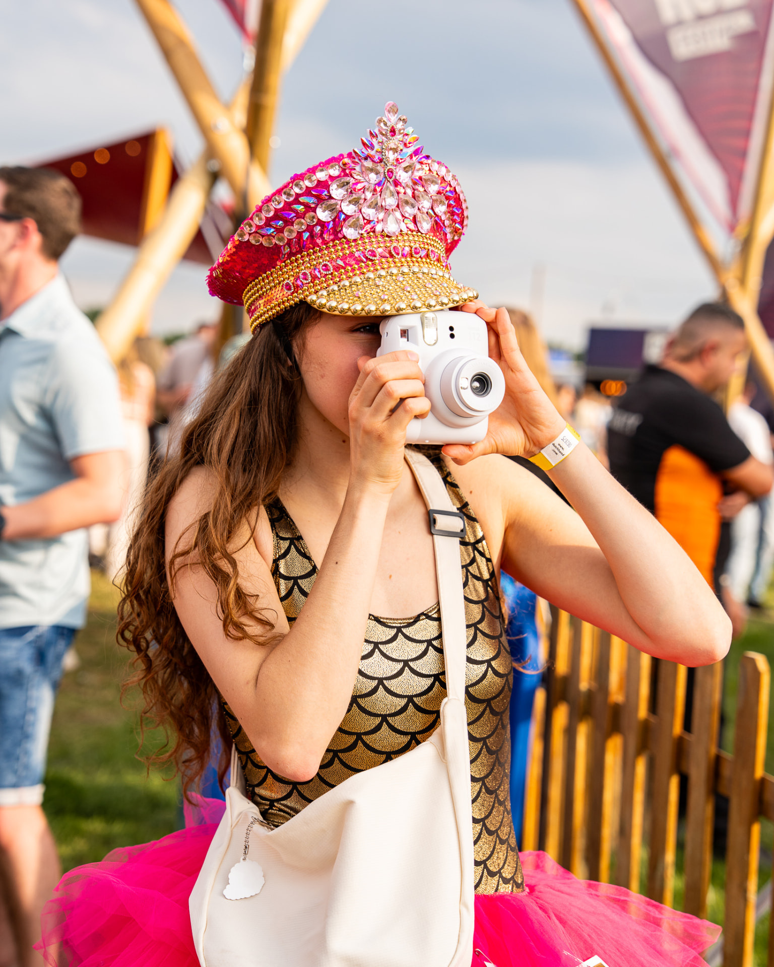 Polaroid Lady met glittercap maakt een foto op het festivalterrein