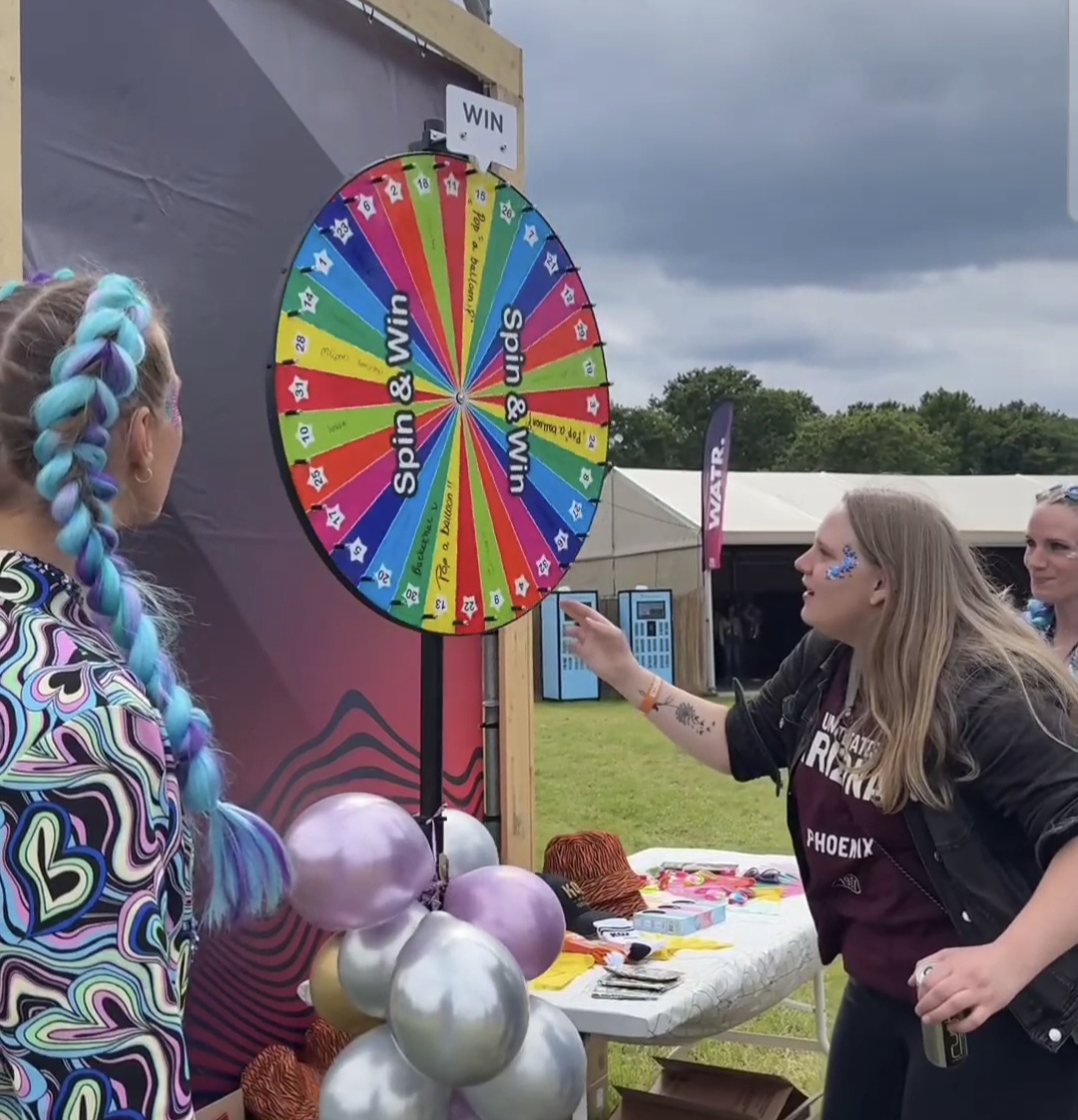 Hostess laat een festivalbezoeker aan het Spin & Win rad draaien